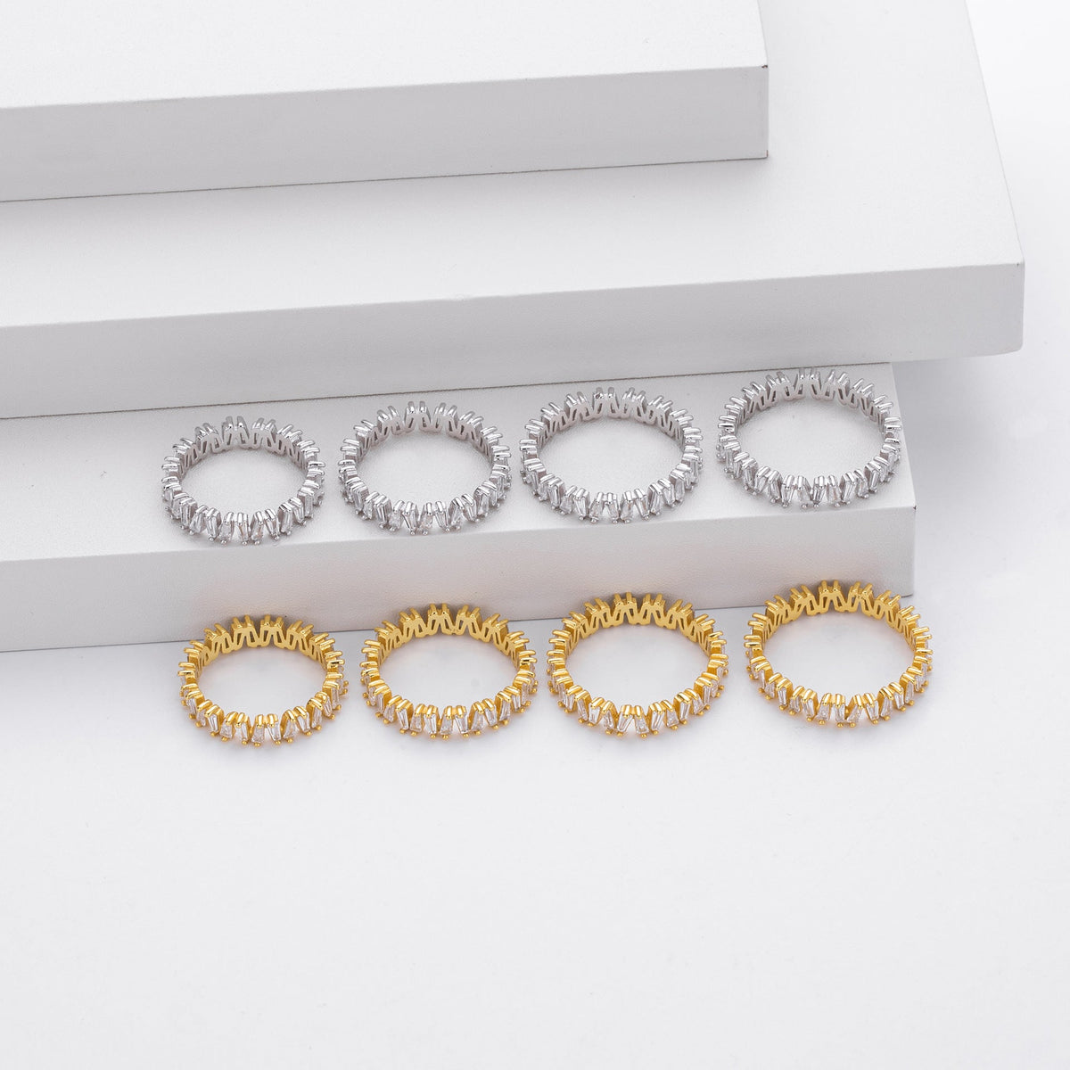 Rows of identical silver and gold-plated rings on a white background